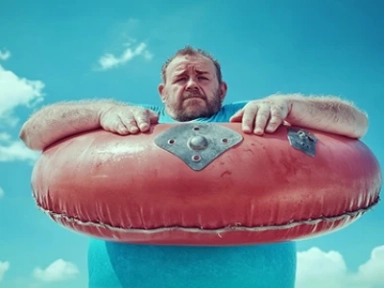 Homem em uma piscina segurando um grande anel de flutuação vermelho.