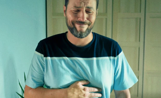 Homem em desconforto segurando seu estômago.