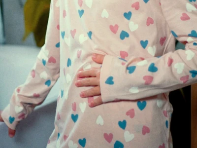 Pessoa com camiseta com estampa de coração segurando suavemente o estômago.