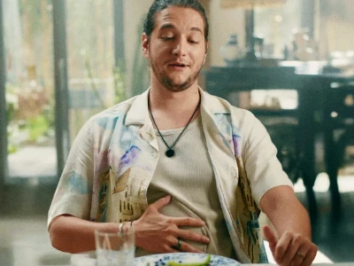 Homem sentado em uma mesa, visivelmente satisfeito, com uma mão sobre o estômago.