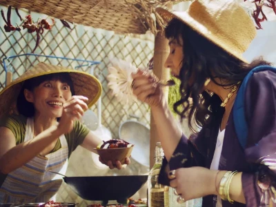 Uma mulher saboreia alimentos em uma vibrante barraca de mercado ao ar livre.