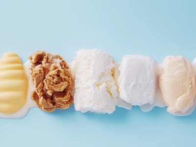 Uma fileira de colheres de sorvete de diferentes sabores em um fundo azul claro.