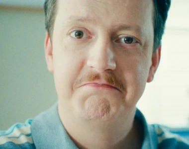 Homem de bigode vestindo uma camisa de colarinho azul-claro.