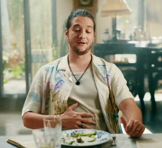 Homem sentado em uma mesa, visivelmente satisfeito, com uma mão sobre o estômago.