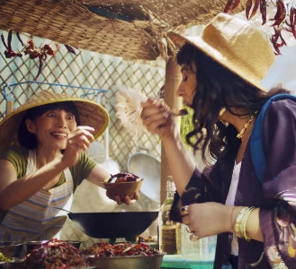 Uma mulher saboreia alimentos em uma vibrante barraca de mercado ao ar livre.