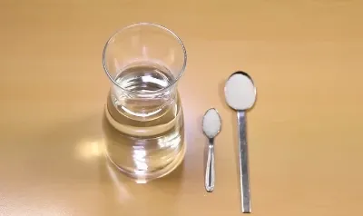 Recipiente com água, uma colher de chá com sal e uma colher de sopa de açúcar.