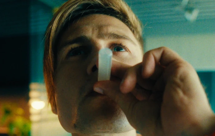 Uma pessoa segurando um inalador nasal branco próximo ao nariz.