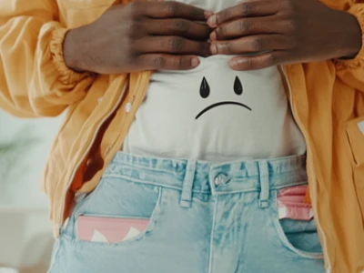 Pessoa revelando uma ilustração de rosto triste em sua camiseta branca.