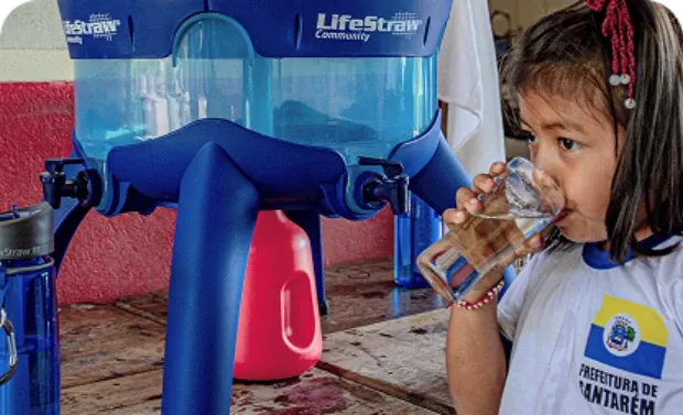 Criança bebendo água de um filtro LifeStraw Community.