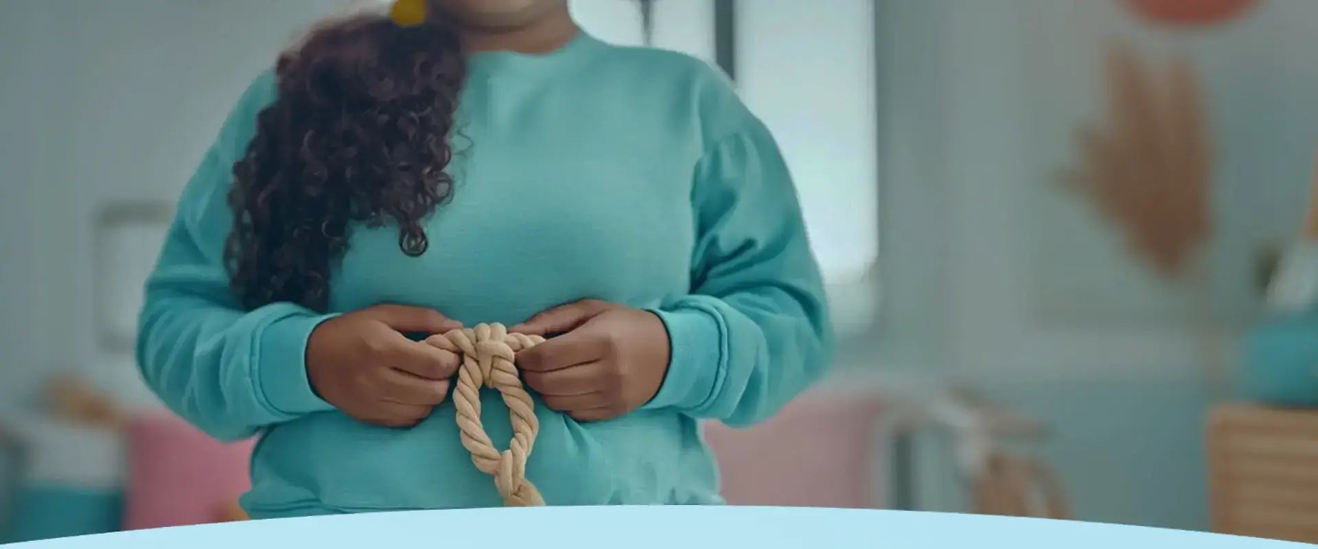 Pessoa com um suéter azul-petróleo segurando uma corda torcida.