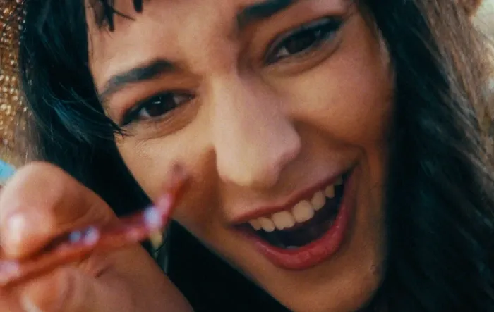 Pessoa sorrindo enquanto segura um objeto perto da câmera.