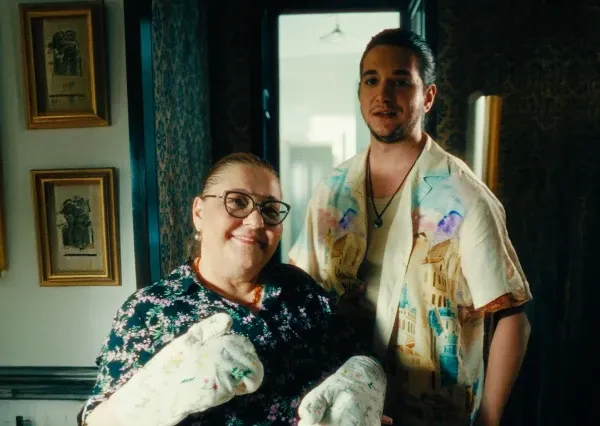 Uma mulher sorridente com luvas de forno está ao lado de um homem com uma camisa colorida.