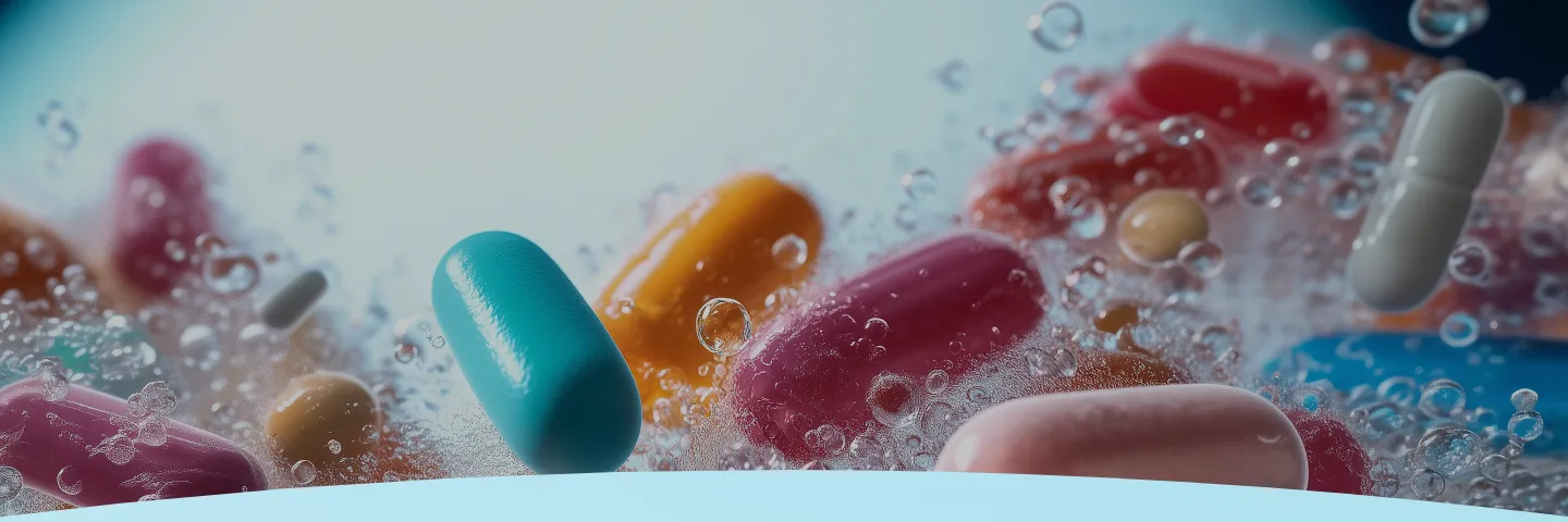 Várias pílulas coloridas submersas em água com bolhas.