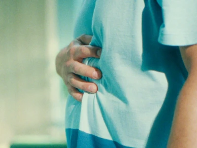 Pessoa segurando o estômago, indicando possível desconforto ou dor.