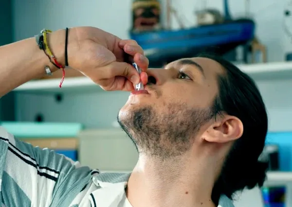 Pessoa que consome um líquido de um pequeno frasco.