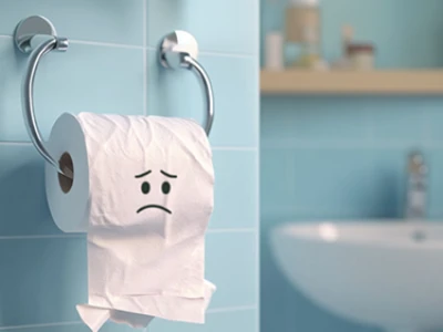 Rolo de papel higiênico com uma cara triste em um ambiente de banheiro.