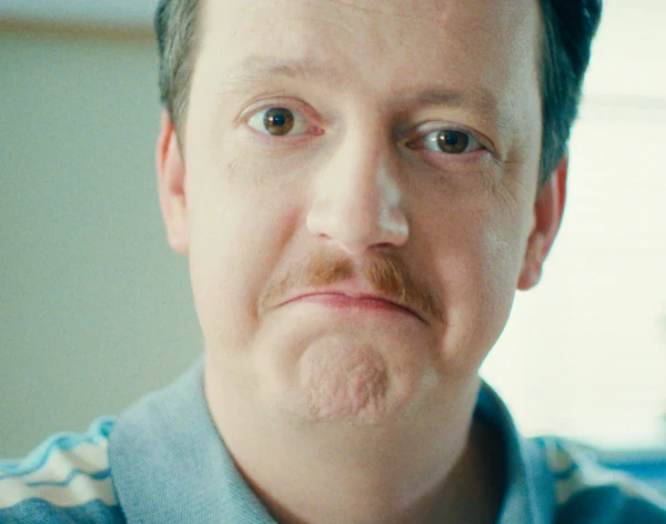 Homem de bigode vestindo uma camisa de colarinho azul-claro.