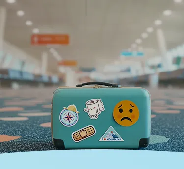 Pequena mala azul com adesivos com tema de viagem em um ambiente de aeroporto.