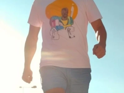 Uma pessoa de tênis caminhando em um calçadão de madeira iluminado pelo sol.