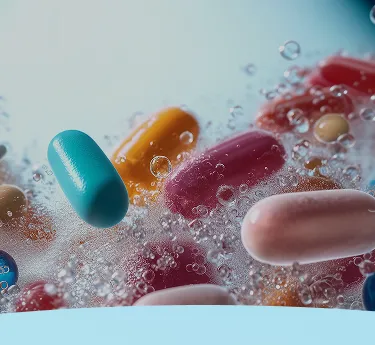 Cápsulas coloridas submersas em um líquido borbulhante.