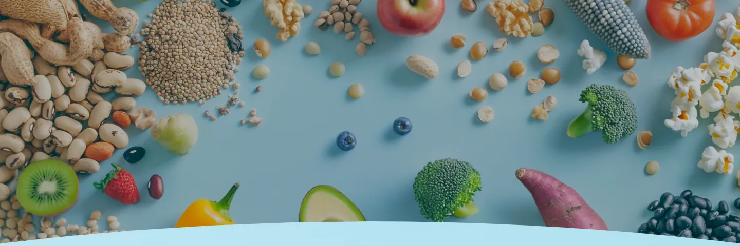 Frutas, legumes, nozes e grãos variados em um fundo azul.