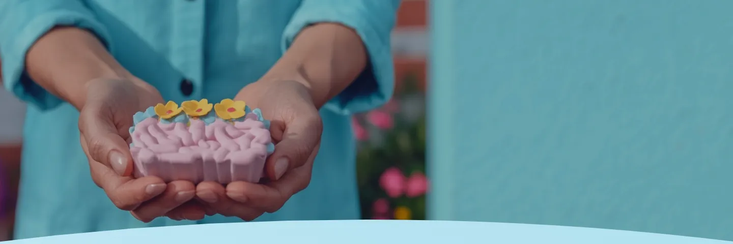 Mãos segurando um sabonete decorativo em forma de bolo com flores amarelas.
