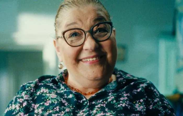 Mulher sorridente usando óculos e uma blusa floral.