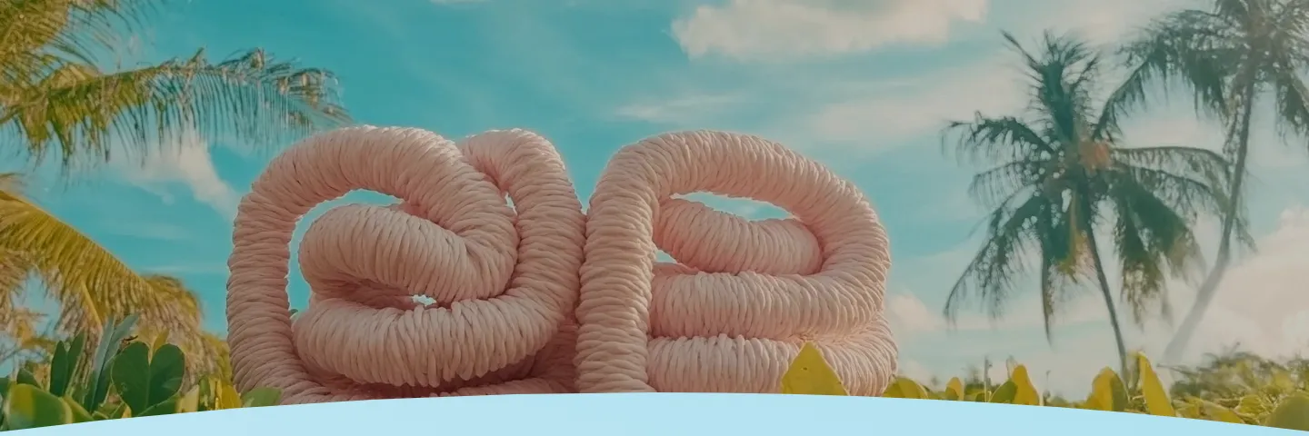 Corda rosa enrolada em frente a palmeiras e um céu azul.