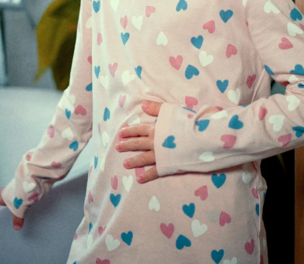 Pessoa com camiseta com estampa de coração segurando suavemente o estômago.