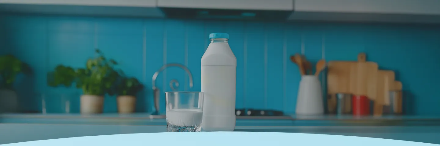 Garrafa e copo de leite em um balcão de cozinha com azulejos azuis.