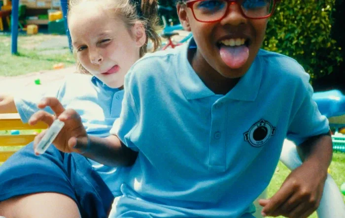 Duas crianças de camisa azul fazendo caretas ao ar livre.