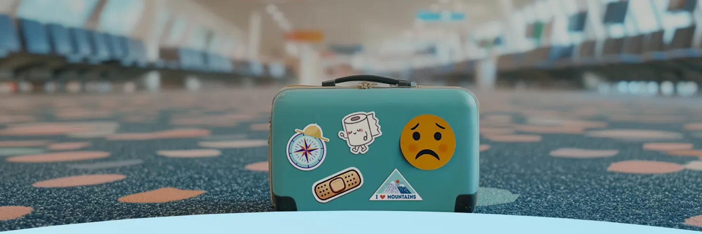 Mala azul-petróleo com adesivos de viagem no chão do aeroporto.