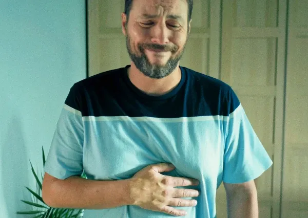 Homem segurando seu estômago com uma expressão de dor.