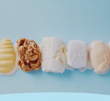 Uma fileira de colheres de sorvete de diferentes sabores em um fundo azul claro.