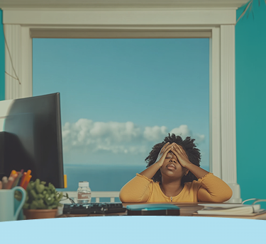 Pessoa sentada em uma mesa, cobrindo o rosto com as mãos, em frente a uma grande janela com vista para o céu azul.