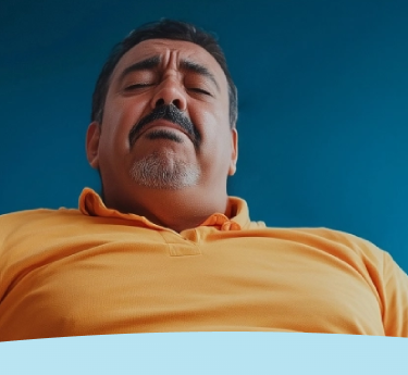 Homem de camisa amarela com os olhos fechados, parecendo estar em desconforto.