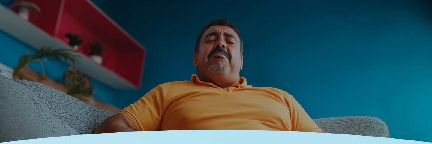 Homem de camisa amarela com os olhos fechados, parecendo estar em desconforto.