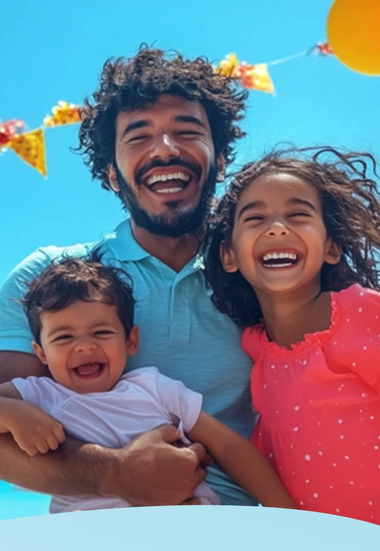 Família sorrindo em uma praia ensolarada com balões e decorações festivas.