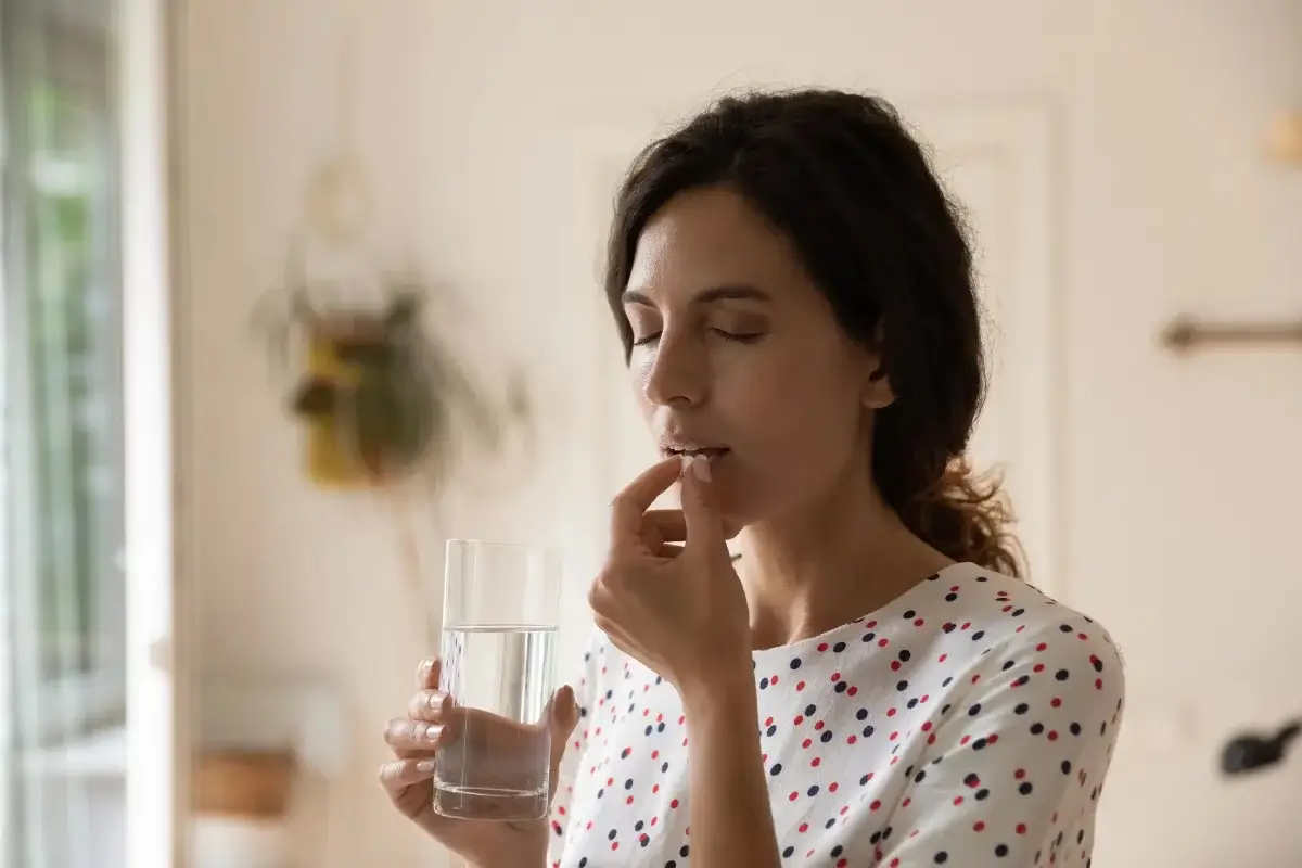 Mujer tomando pastilla de antibioticos.