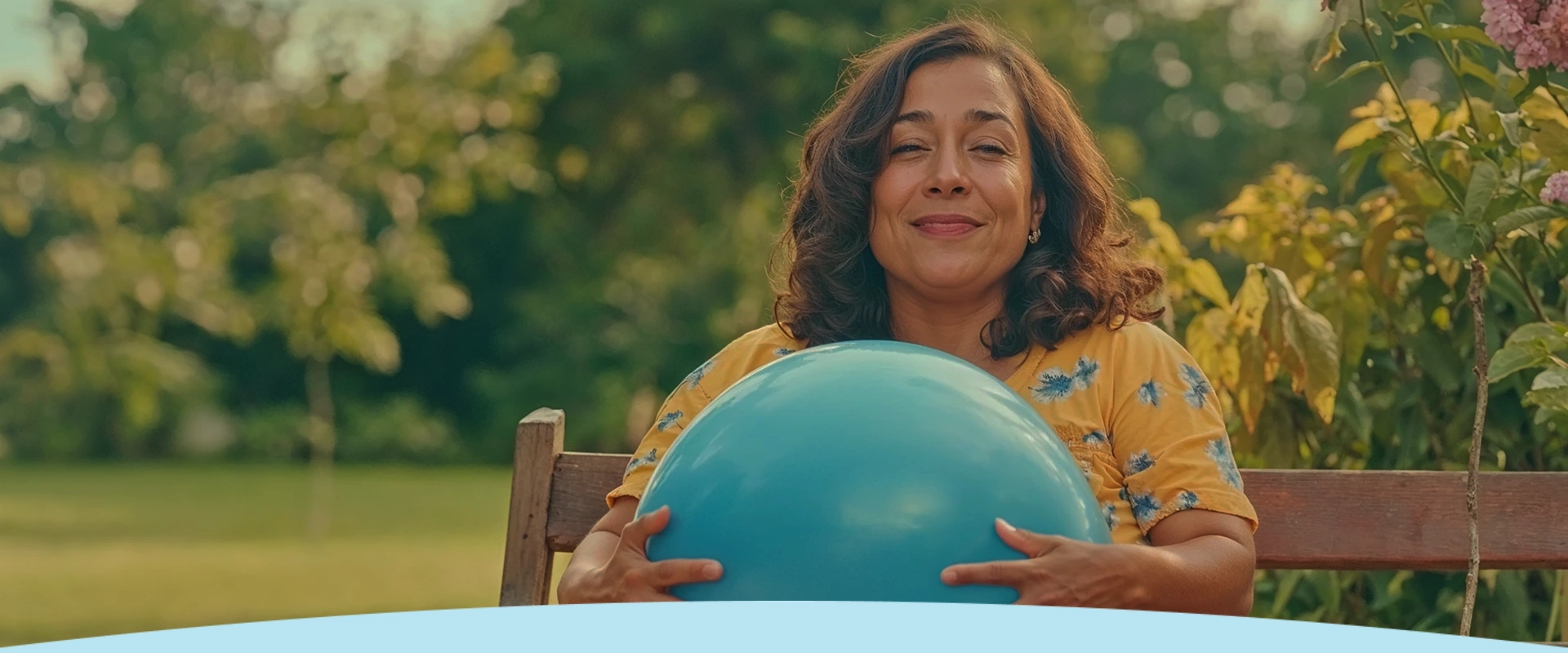 Mulher sorrindo enquanto segura uma bola de exercícios azul ao ar livre.