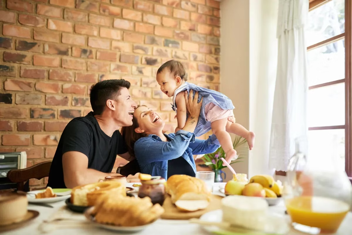 Padres y su bebé disfrutando la hora del desayuno. Los probióticos ayudan a fortalecer la microbiota.