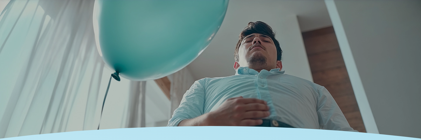 Homem olhando para cima com os olhos fechados, vestindo uma camisa azul clara.