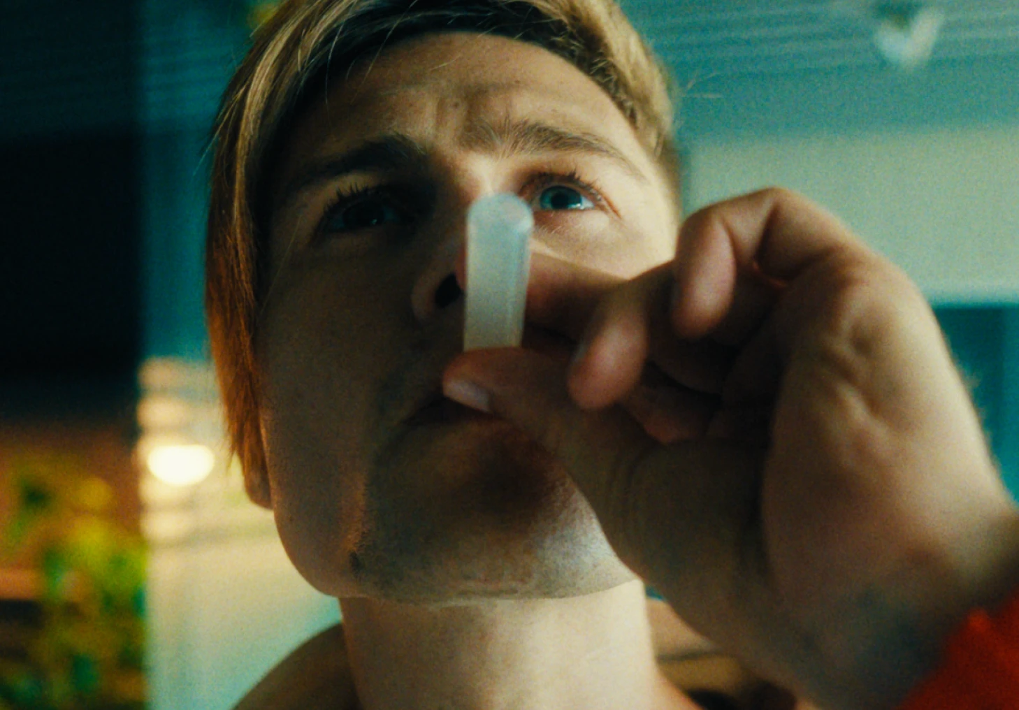 Uma pessoa segura um picolé perto de seus lábios em um ambiente fechado.