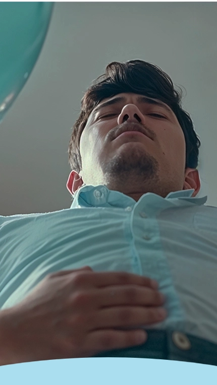 Pessoa deitada com a mão sobre o estômago, vestindo uma camisa azul clara.