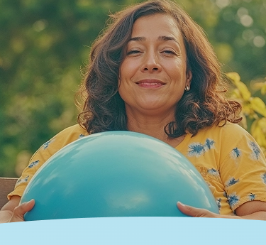 Mulher segurando uma grande bola azul, sorrindo ao ar livre.