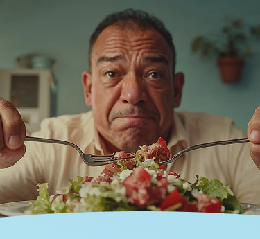 Homem segurando garfo e faca, olhando para uma salada com uma expressão preocupada.