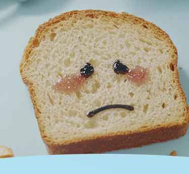 Fatia de pão com uma cara triste feita de geleia e chocolate.