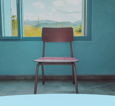 Cadeira de madeira em frente a uma janela aberta mostrando uma paisagem cênica.